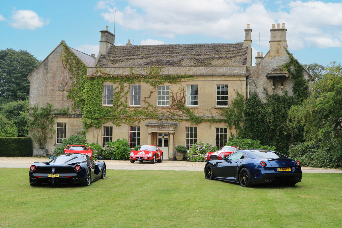 The exterior of Middlewick House, with five sports cars parked on the lawn in front