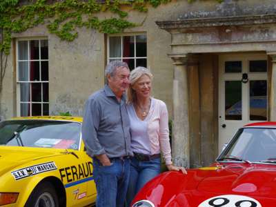A photo of Nick and Annette Mason in front of the Middlewick House and two sports cars.
