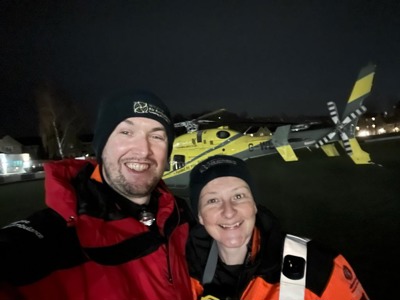 A selfie of a doctor and paramedic at night, in front of the helicopter