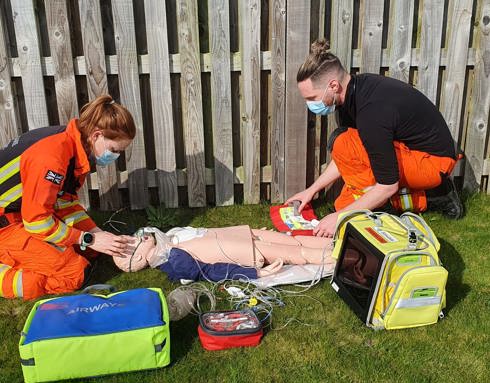 Paramedic Sophie And Dr Jono Training on a manikin, surrounded by kit bags