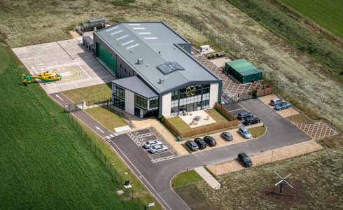 An aerial photo of the Wiltshire Air Ambulance airbase with the helicopter landing on its helipad.