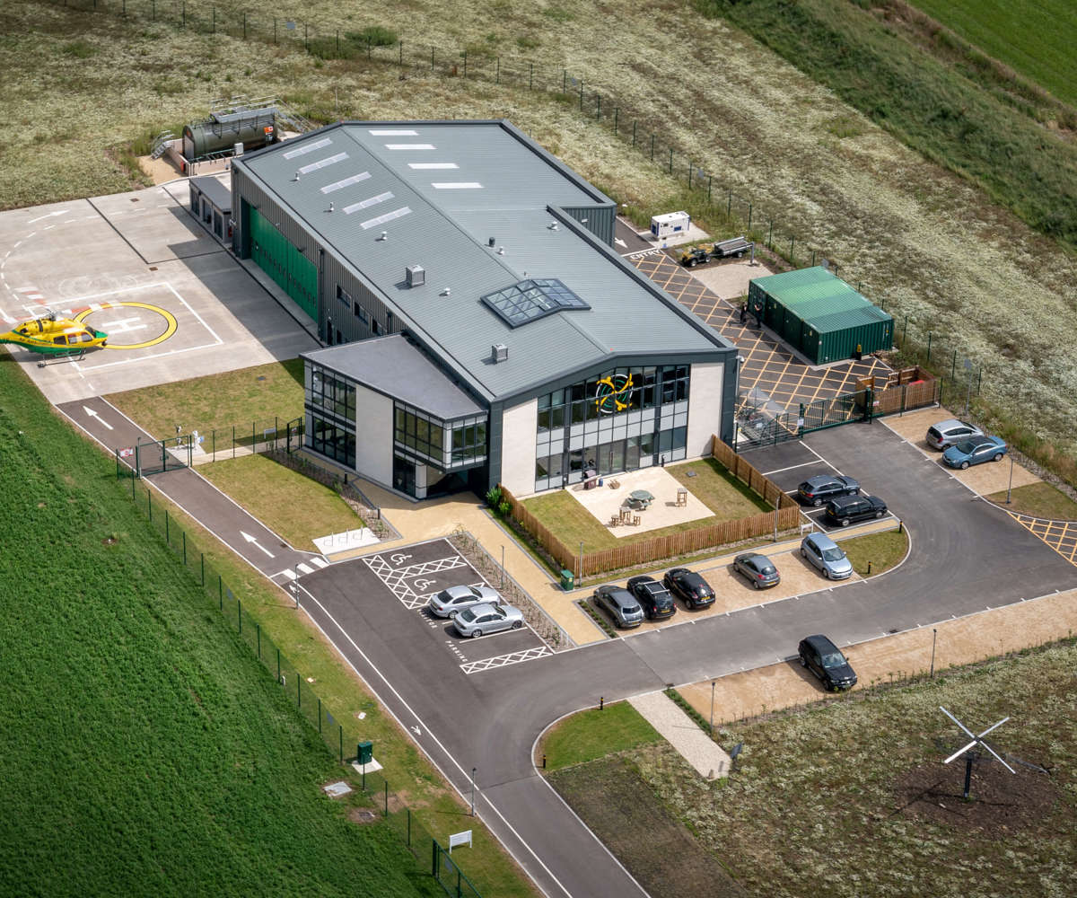 An aerial photo of the Wiltshire Air Ambulance airbase featuring the Bell-429 helicopter landing on its helipad.