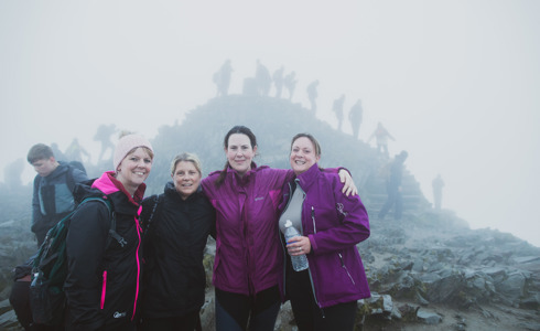 A group of 4 women posing for a photo at the top of Mount Snowdon