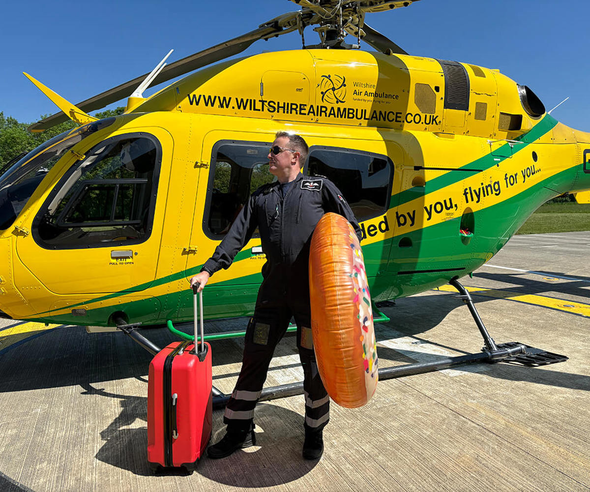 A pilot stood in front of the WAA helicopter with a suitcase and giant inflatable