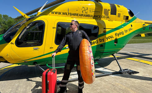 A pilot stood in front of the WAA helicopter with a suitcase and giant inflatable