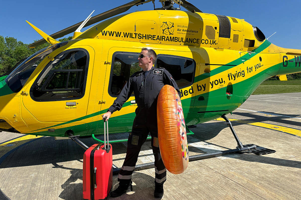 A pilot stood in front of the WAA helicopter with a suitcase and giant inflatable