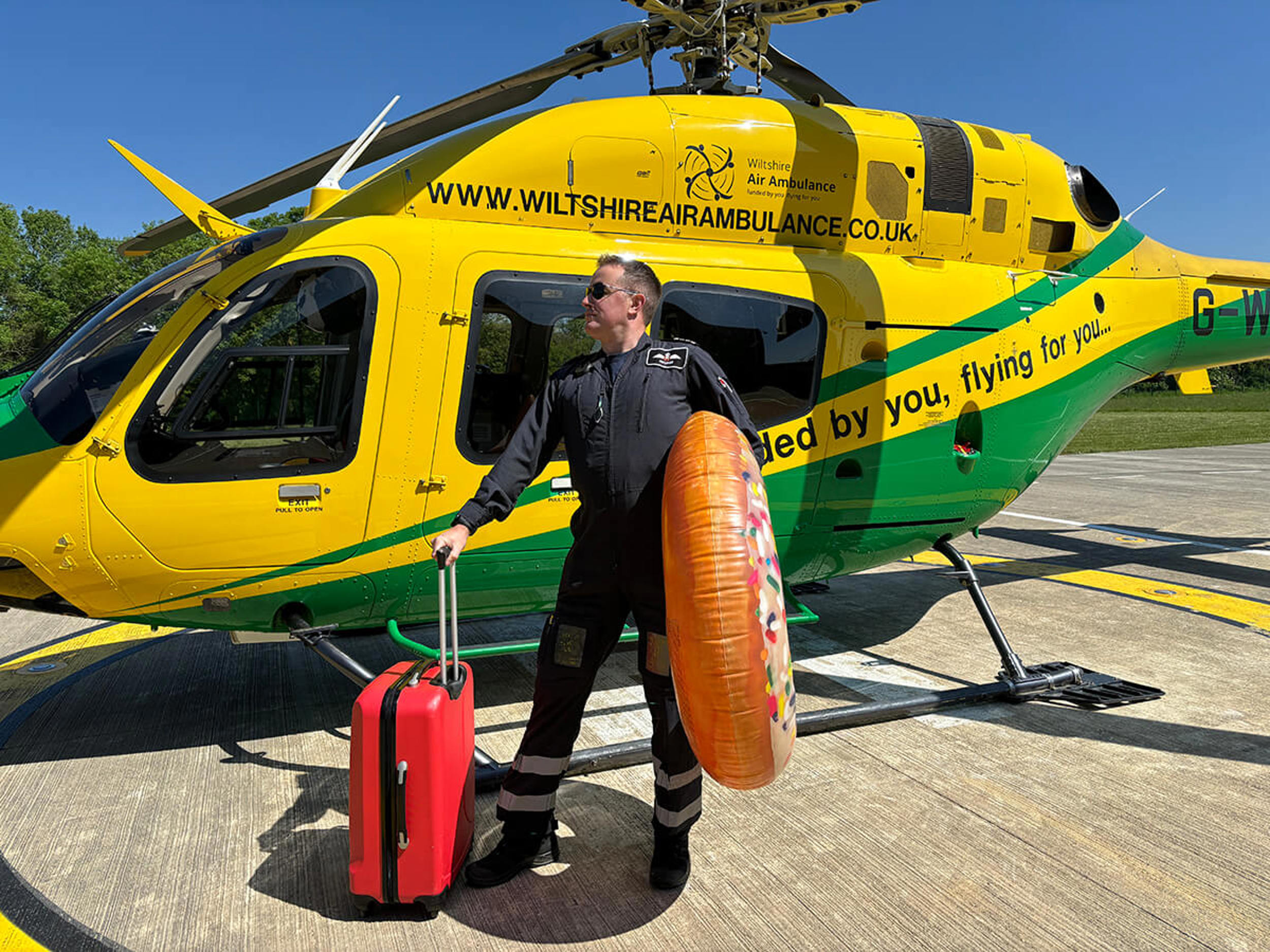 A pilot stood in front of the WAA helicopter with a suitcase and giant inflatable